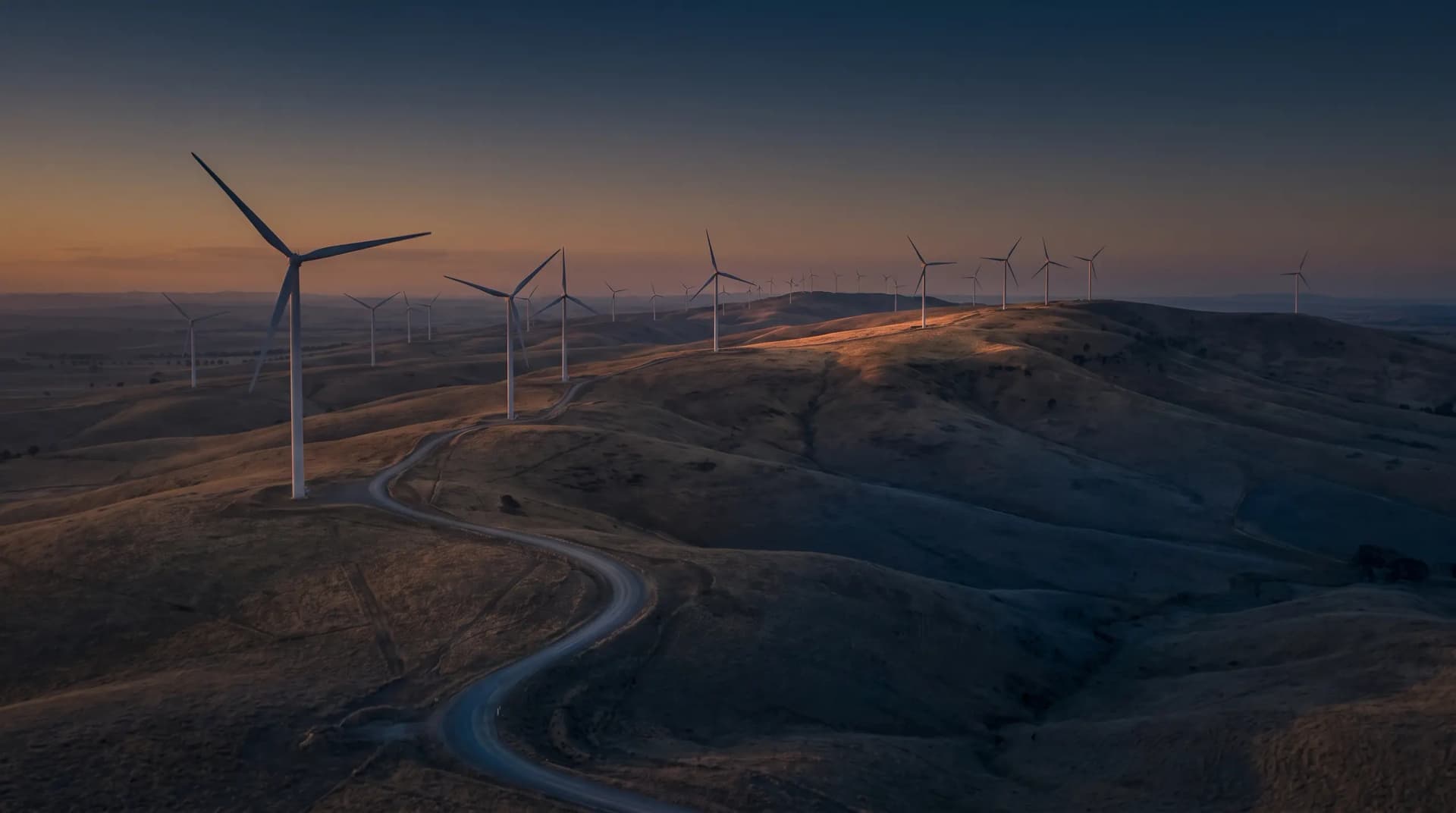 Wind turbines across rolling hills at dusk